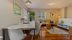 Ein modernes Wohnzimmer mit Essbereich, einer Couch, einem Couchtisch und einem Bücherregal.