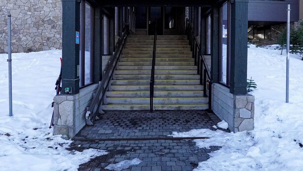L’entrée d’un immeuble, avec une enseigne indiquant « Snowcrest Lodge » et le numéro « 1215 ».
