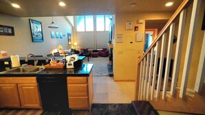 Une cuisine dotée d’un îlot central, un coin repas avec une table et des chaises, et un escalier menant à un autre niveau.