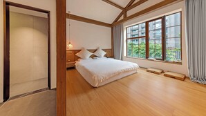 A spacious bedroom with a large bed, wooden beams on the ceiling, a window with a view of greenery, and a bedside table with a lamp. - Shanjue Cultural Boutique Hotel-Nanbin (Chongqing)