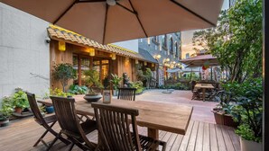 An outdoor patio with wooden furniture, potted plants, and a tiled roof. - Shanjue Cultural Boutique Hotel-Nanbin (Chongqing)
