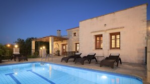 Ein Swimmingpool mit Liegestühlen und ein Gebäude mit Fenster.