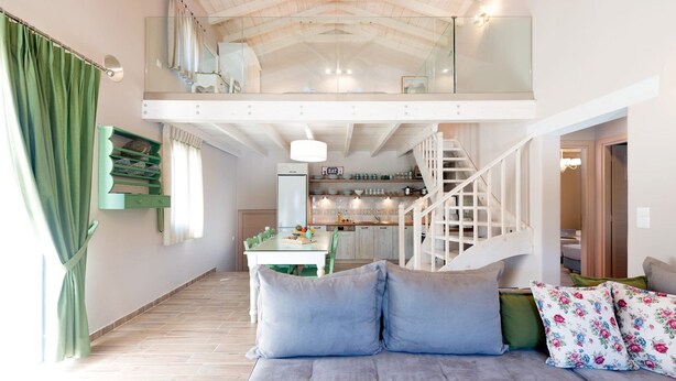 Un'ampia camera da letto mansardata con soffitto alto, un balcone, un'area pranzo e una cucina.
