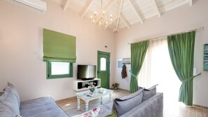 Un soggiorno con un divano, un tavolino, una TV e una porta verde.