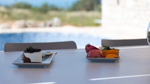 Un tavolo con un dessert e una ciotola di frutta, con vista su una piscina e sul verde.