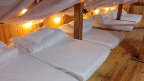A row of wooden beds with white linens, covered by a white canopy. - To Ech Homestay (Sin Suoi Ho)
