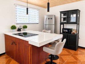 Een moderne keuken met een centraal eiland, ingebouwde apparatuur en een zwart kastje met glazen deuren.