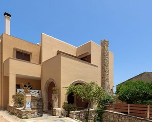 A modern building with a beige facade, stone chimney, and arched entryways. - Villa Nephele, 3 BDR, Forest Views, Private Pool, Furnished Terrace, Crete (Rethymno)