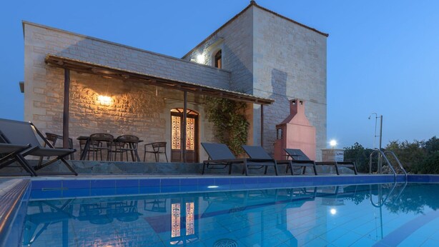 Ein modernes Gebäude mit Pool, Sitzgelegenheiten im Freien und einer Steinfassade.