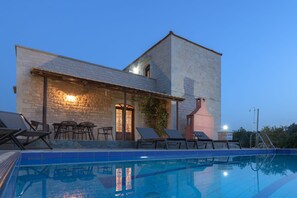 Ein modernes Gebäude mit Pool, Sitzgelegenheiten im Freien und einer Steinfassade.
