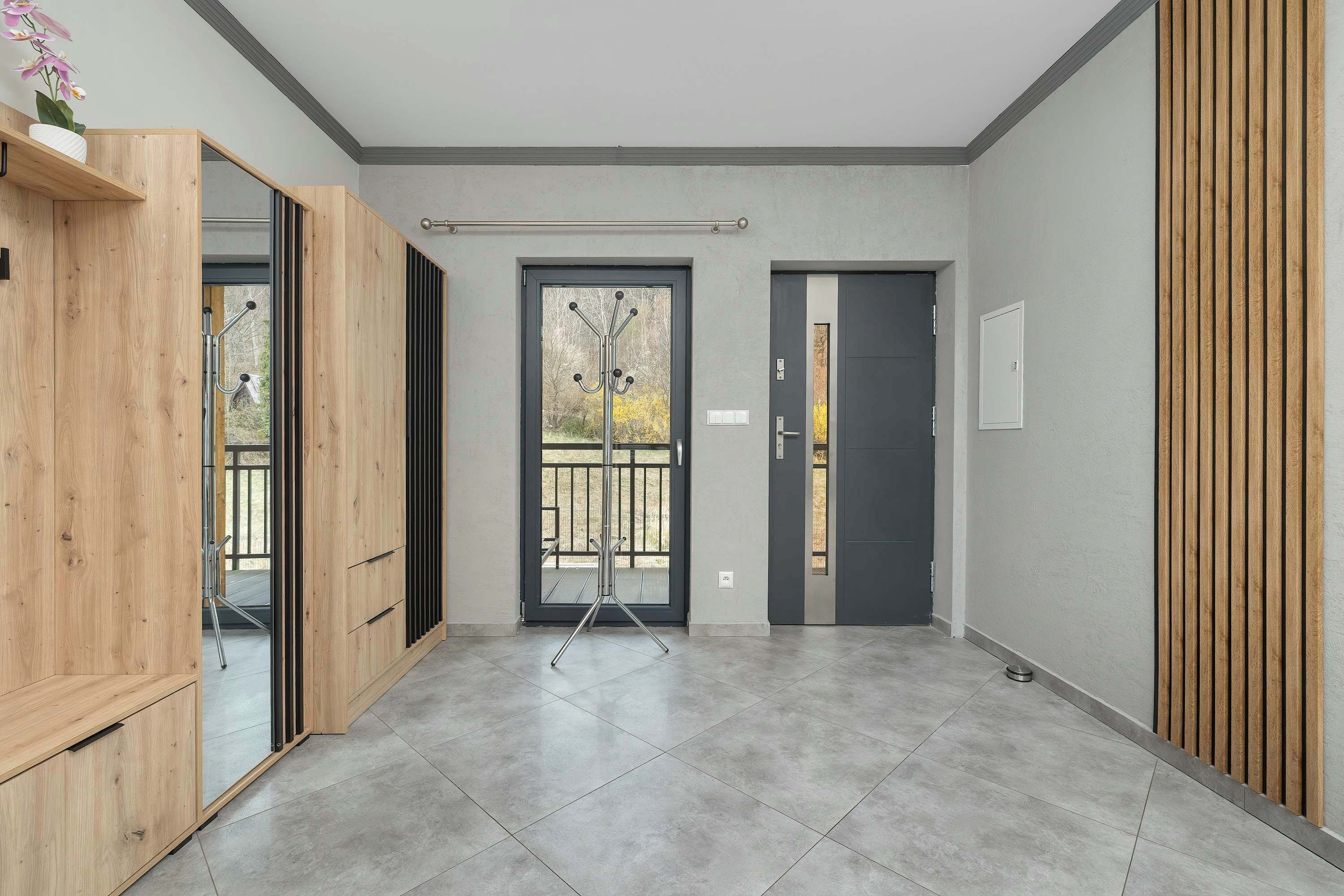 A modern interior with a wooden wardrobe, a glass door entrance, and a tiled floor.