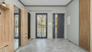A modern interior with a wooden wardrobe, a glass door entrance, and a tiled floor.