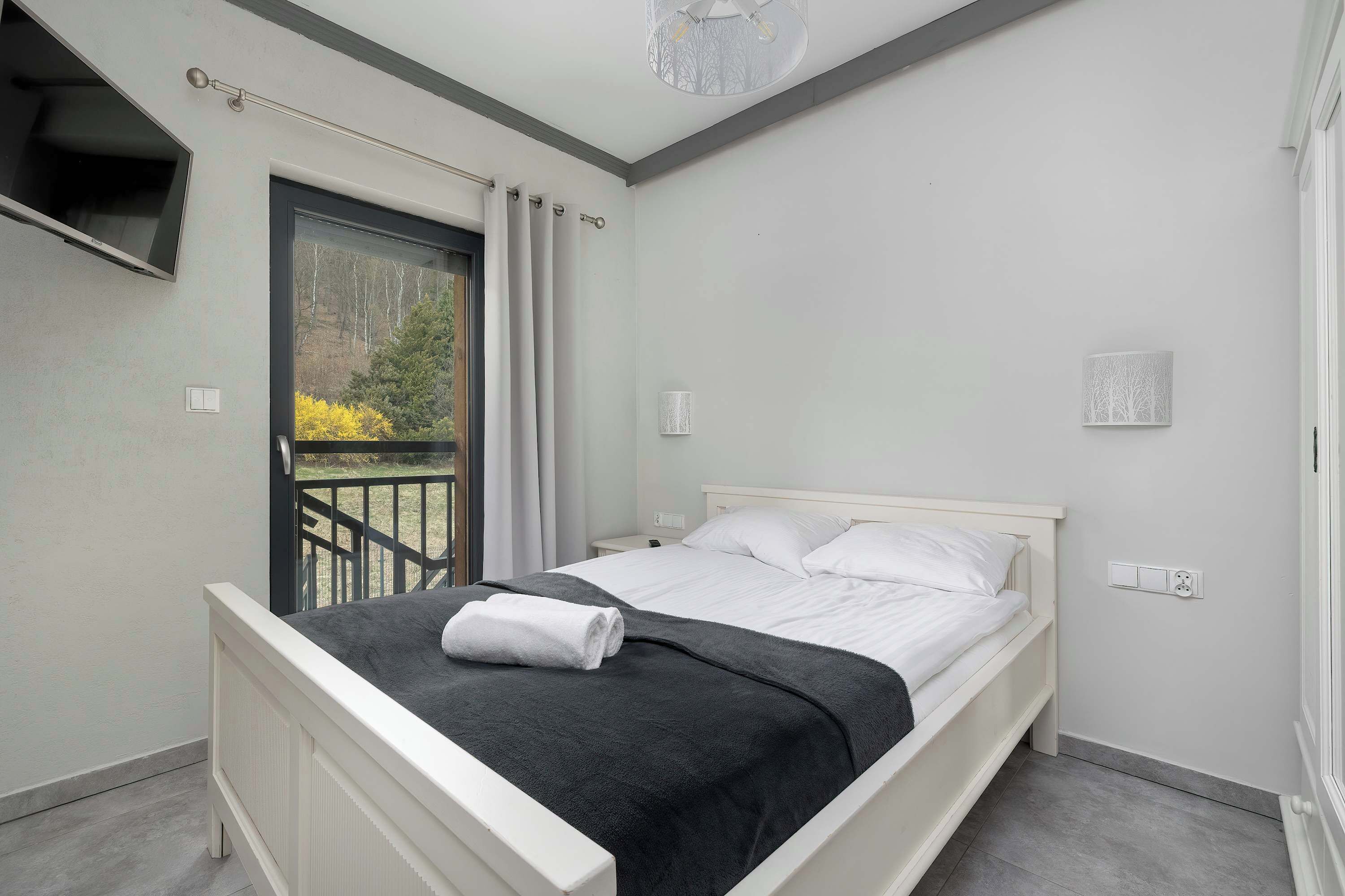 Une chambre à coucher avec un lit, une fenêtre, une porte et une vue sur les arbres.