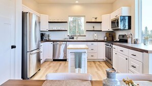 Une cuisine moderne avec des meubles blancs, des appareils en acier inoxydable et un plan de travail en bois.