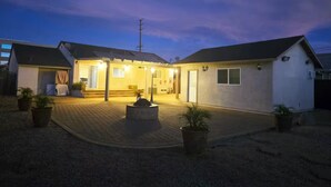 A residential property with a paved driveway, a covered outdoor seating area, and a well-lit entrance. - Spacious 3-Bed Home w/ Bonus Room in Loma Linda CA (Loma Linda)