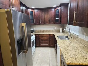 Eine Küche mit dunklen Holzschränken, einem Edelstahlkühlschrank, einer Granitarbeitsplatte und einem eingebauten Ofen.