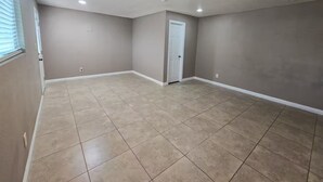 A spacious room with beige tiled flooring, a white door, and recessed ceiling lights. - Spacious 3-Bed Home w/ Bonus Room in Loma Linda CA (Loma Linda)