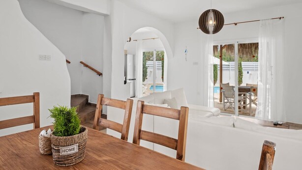 Um interior moderno com uma mesa de jantar de madeira, sofás brancos e uma escadaria.