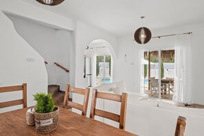Um interior moderno com uma mesa de jantar de madeira, sofás brancos e uma escadaria.