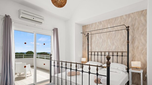 A bedroom with a four-poster bed, a balcony with white chairs, and a view of the sky. - Villa Kallidora, 4 BDR, Private Pool, Furnished Terrace, Ayia Napa, Cyprus (Famagusta)