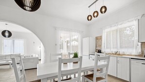 A modern kitchen with white cabinetry, a white dining table with four chairs, and a built-in dishwasher. - Villa Kallidora, 4 BDR, Private Pool, Furnished Terrace, Ayia Napa, Cyprus (Famagusta)