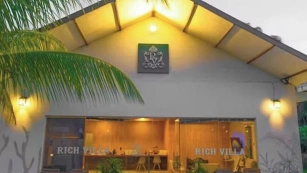 A modern building with a reception area, labeled "RICH VILLA," featuring a welcoming entrance, seating area, and potted plants. - Rich Villa  (Semporna)