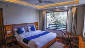 Ein Schlafzimmer mit einem hölzernen Bett, einem Nachttisch, einem Sessel, einem kleinen Tisch und einem Fenster mit Vorhängen.