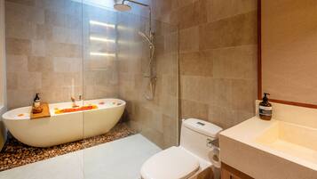 Een aparte badkuip en douche, een haardroger, handdoeken, zeep