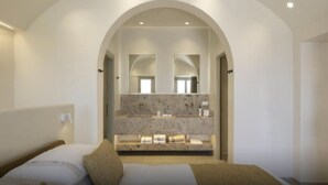 Een moderne slaapkamer met een grote, gebogen doorgang naar een badkamer, met een marmeren aanrechtblad en een grote spiegel.
