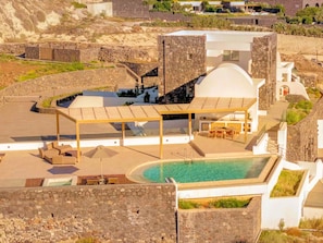 Eine moderne Villa mit Pool, Sitzgelegenheiten im Freien und Steinarchitektur.