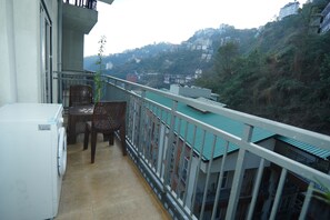A balcony with a washing machine, a table, and chairs. - CDS Luxury Homestay Shimla (Shimla)
