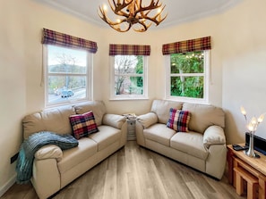 A cozy corner with a beige sofa, plaid cushions, and a wooden floor. - Beautiful modern first floor apartment in Banchory. (Banchory)