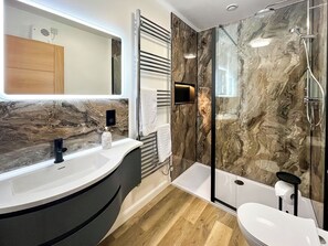 A modern bathroom with a marble vanity, a glass-enclosed shower, and a built-in toilet.