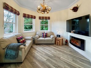 A cozy living room with a fireplace, a sofa, a loveseat, and a TV mounted on the wall. - Beautiful modern first floor apartment in Banchory. (Banchory)