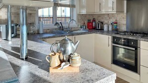Een moderne keuken met een granieten aanrechtblad, roestvrijstalen apparatuur en uitzicht naar buiten.