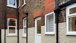 A brick building with white-framed windows and a small grassy area in front. - The Quay & Coast Escape (Bridlington)