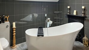 A modern bathroom with a freestanding bathtub, a skylight, and a black tiled wall. - The Quay & Coast Escape (Bridlington)