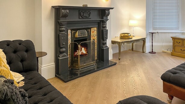 A living room with a fireplace, a sofa, a small table, and a lamp. - The Quay & Coast Escape (Bridlington)