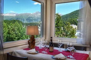 Ein Esstisch mit Weinglas, Karaffe und Lampe, mit Blick auf eine gebirgige Landschaft.