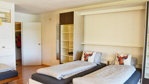 A bedroom with two beds, a wardrobe, and a built-in shelving unit. - Mountain Loft - DuLac 33 (Sankt Moritz)
