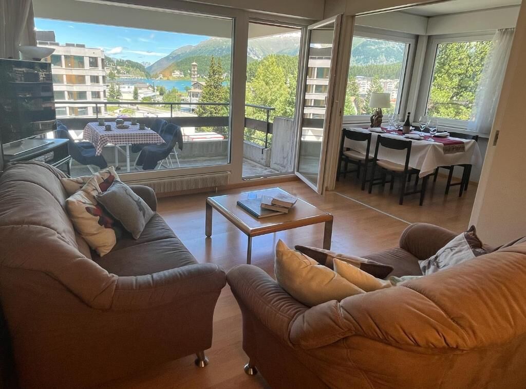 A living room with a sofa, a coffee table, and a dining area with a table and chairs.