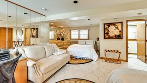 Una habitación amplia con una cama grande, un sofá, un escritorio y un espejo.