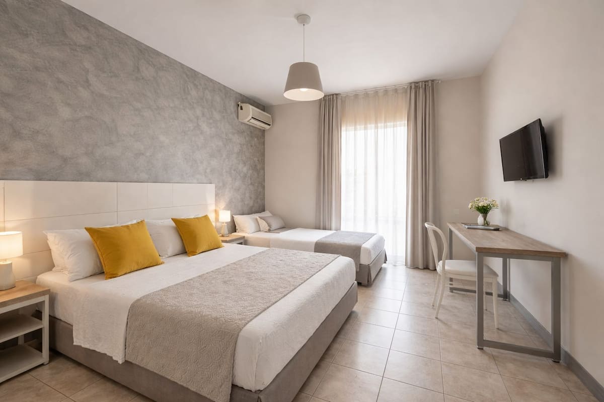 A hotel room with a large bed, two bedside tables, a desk, and a TV.