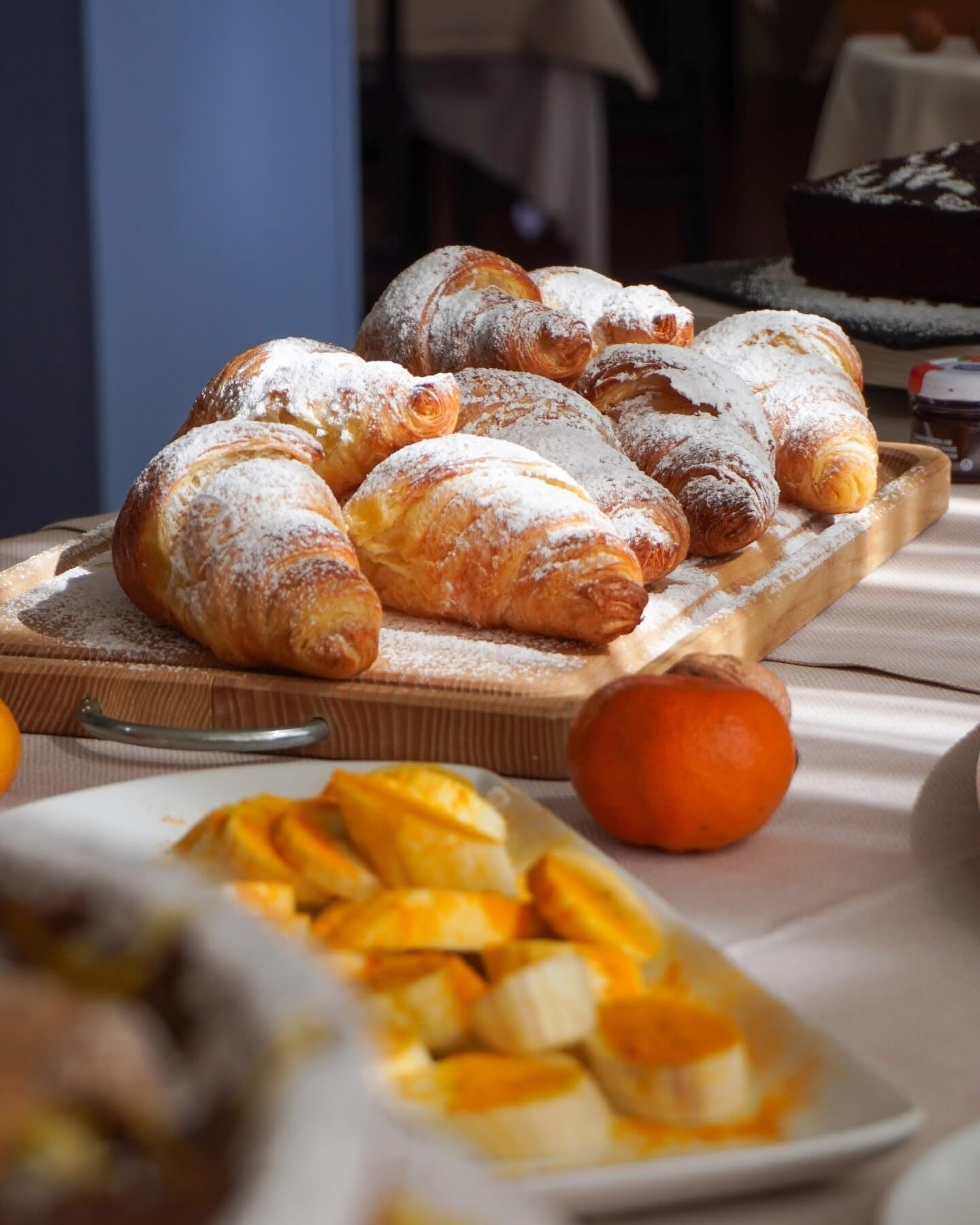 Une planche en bois sur laquelle sont disposées des pâtisseries saupoudrées de sucre glace.