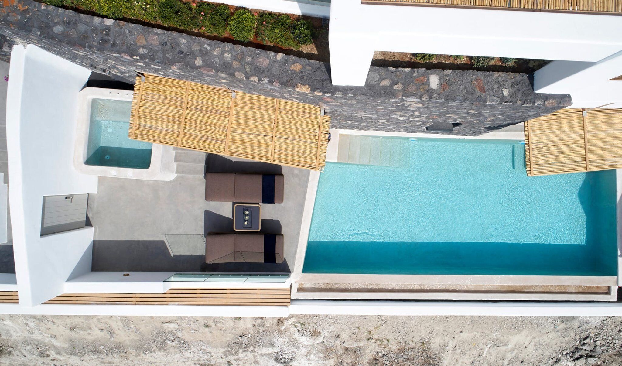 Eine Vogelperspektive auf einen modernen Poolbereich mit einem großen rechteckigen Pool, einer Whirlpoolanlage und einer Sitzgelegenheit mit Tisch und Stühlen.