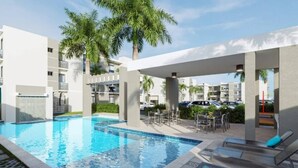 A swimming pool with lounge chairs and palm trees, surrounded by modern buildings. - Moderno Apto en B Varo Island Piscina Playa (Punta Cana)