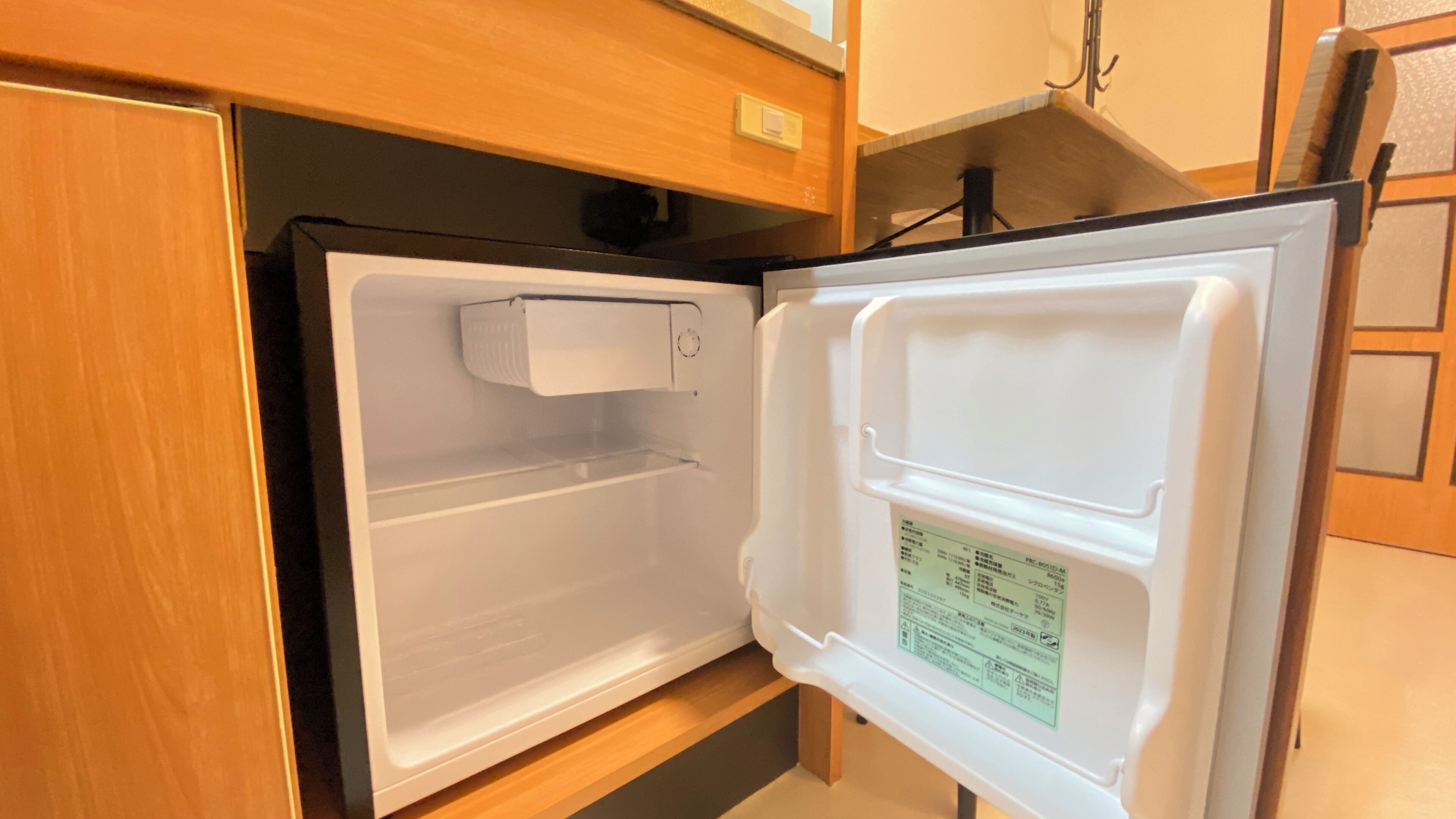 Ein offener Kühlschrank mit Bedienfeld an der Tür, einer Ablage und einem Gefrierfach.