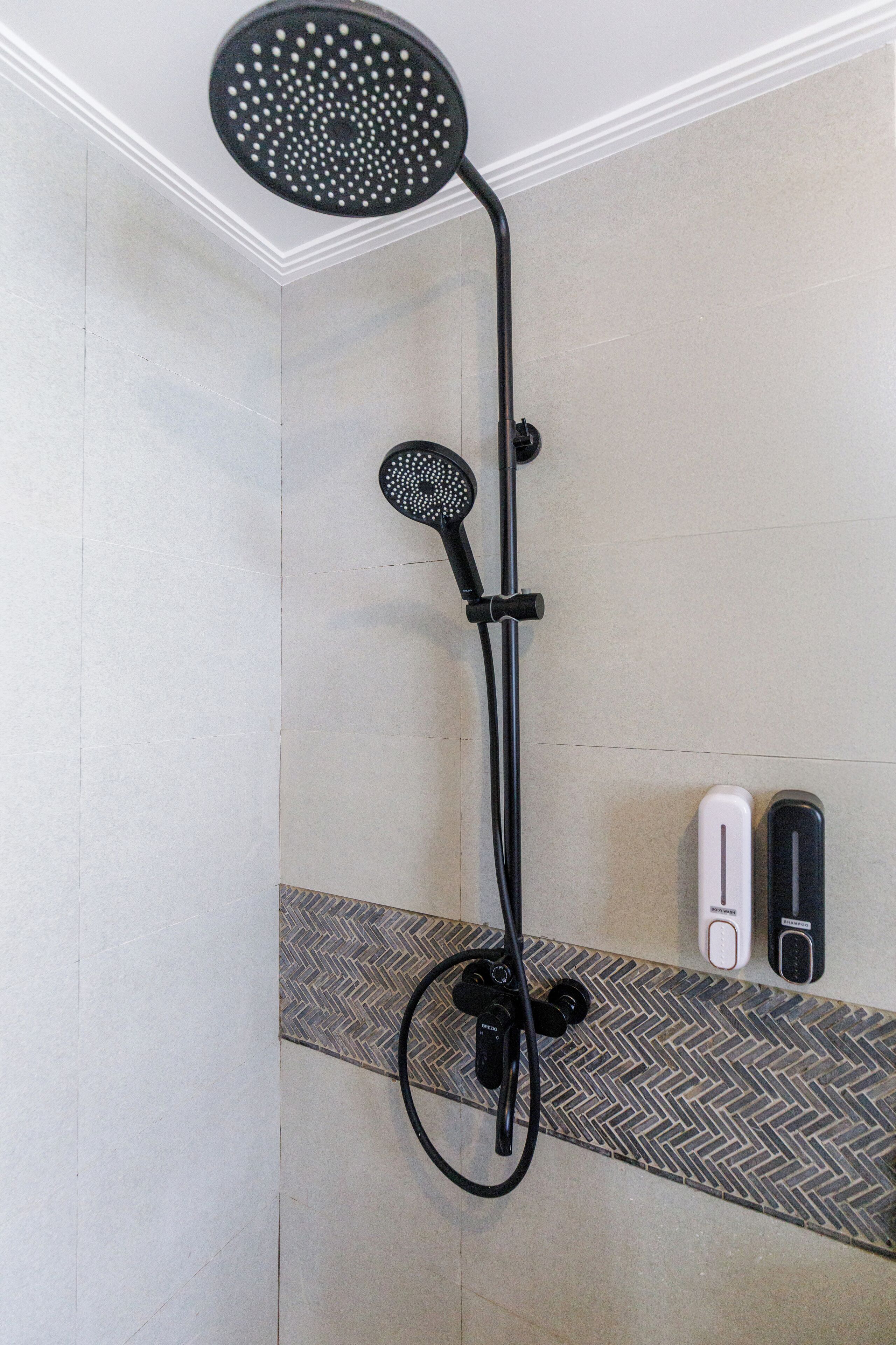 A shower with a handheld showerhead and a wall-mounted control panel.