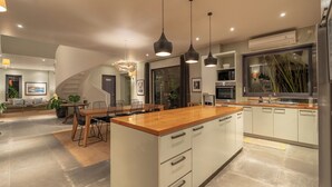 A modern kitchen with a central island, pendant lighting, and a view of the living area. - Villa Ixora by Alfred in Bali (Canggu)
