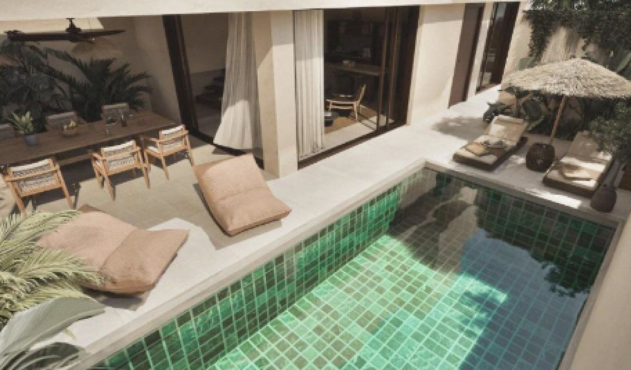 A pool area with a tiled floor, a seating area with chairs and cushions, and a dining table with chairs.